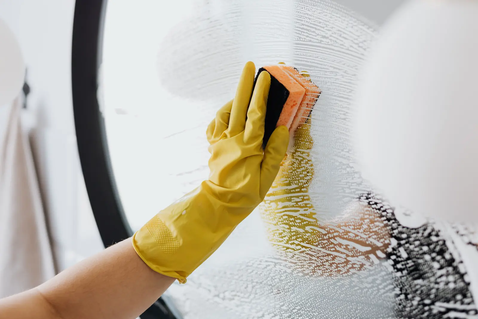 Gloved hand scrubbing a glass surface