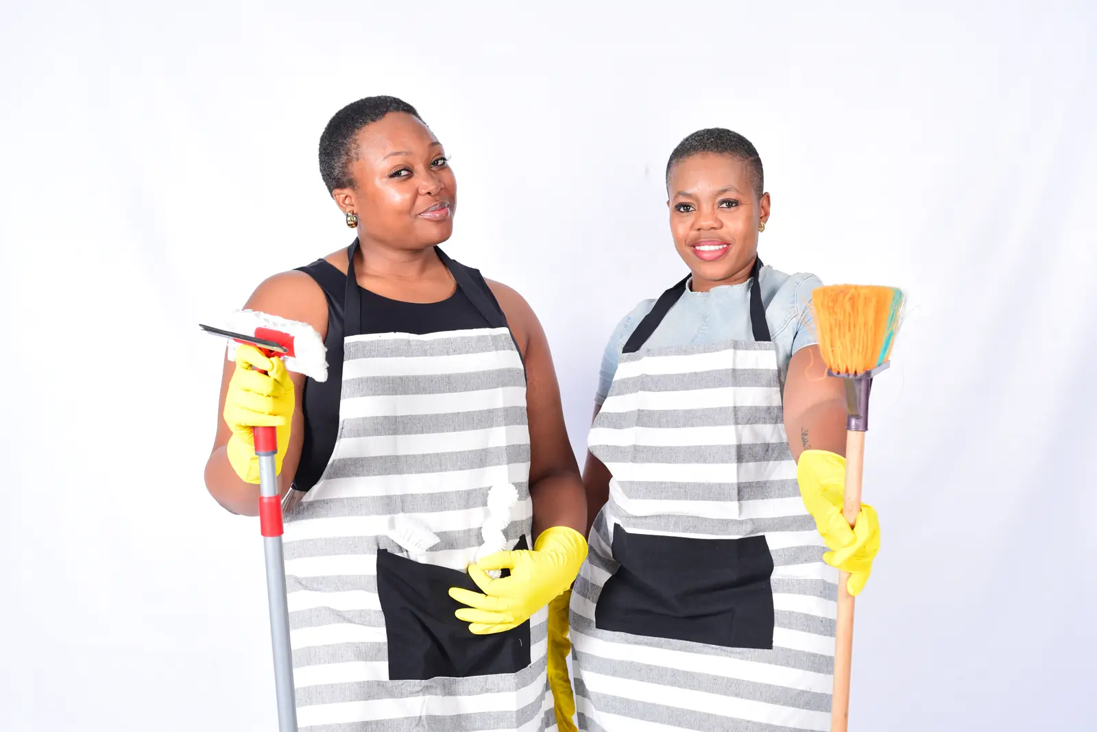 Two OLUMKA team members in striped aprons holding cleaning tools